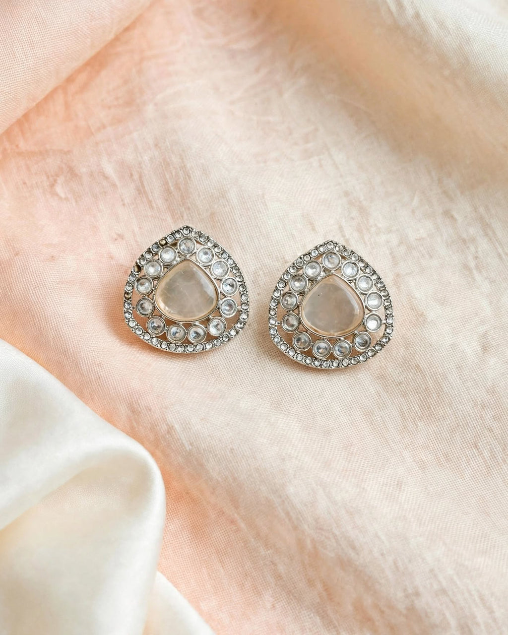 Milky white teardrop earrings with clear round accents and detailed silver-tone borders